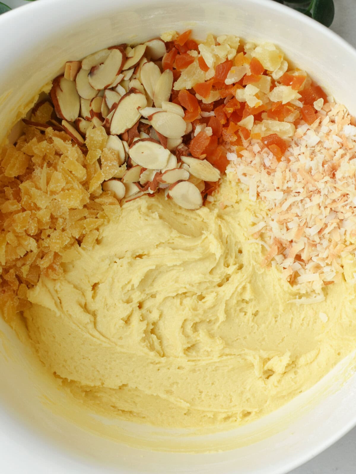 Flour, butter, salt, almonds, coconut, and tropical dried fruit in a mixing bowl.