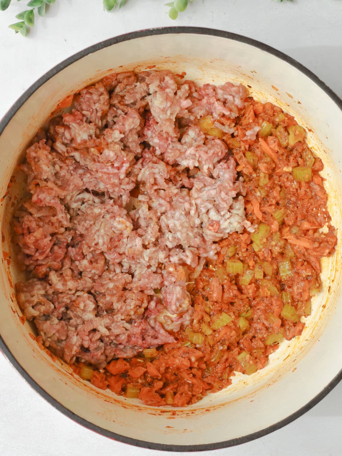 Italian sausage browning in a pan with vegetables. 