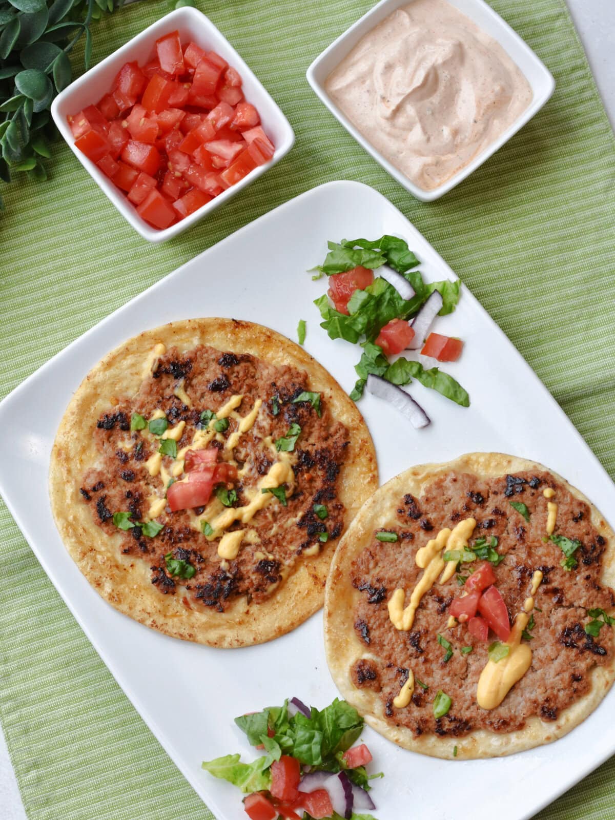 Smash Burger Tacos made with ground pork and chorizo with chipolte sauce and tomato for garnish. 