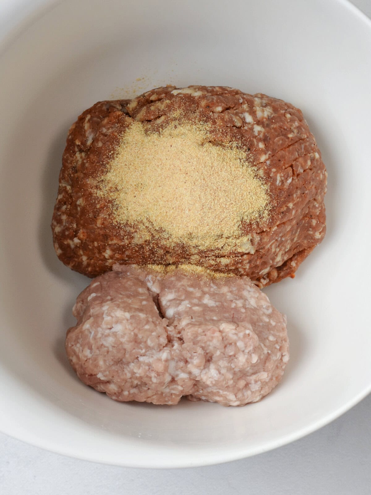 Ground pork, chorizo and seasoning in a mixing bowl. 